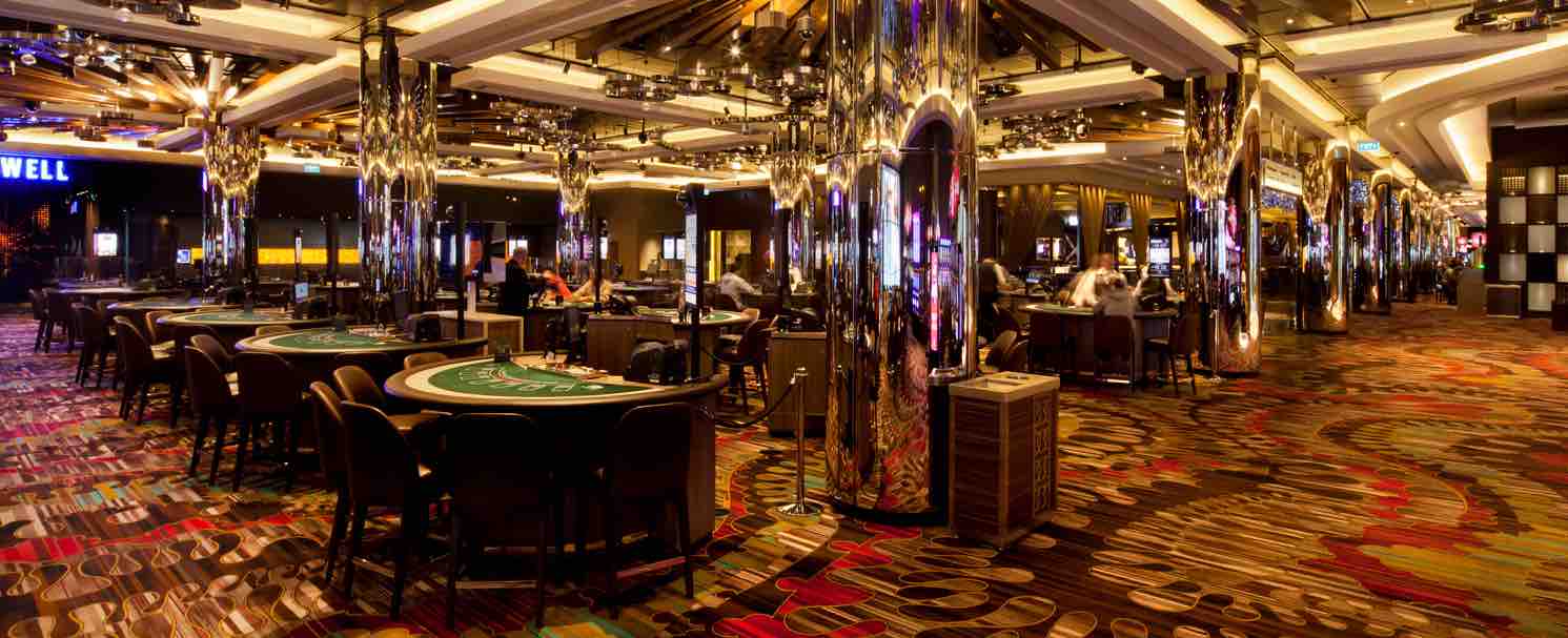 A Melbourne casino room with many tables of black jack, roulette and other games in a carpeted room with bright lighting and a modern style