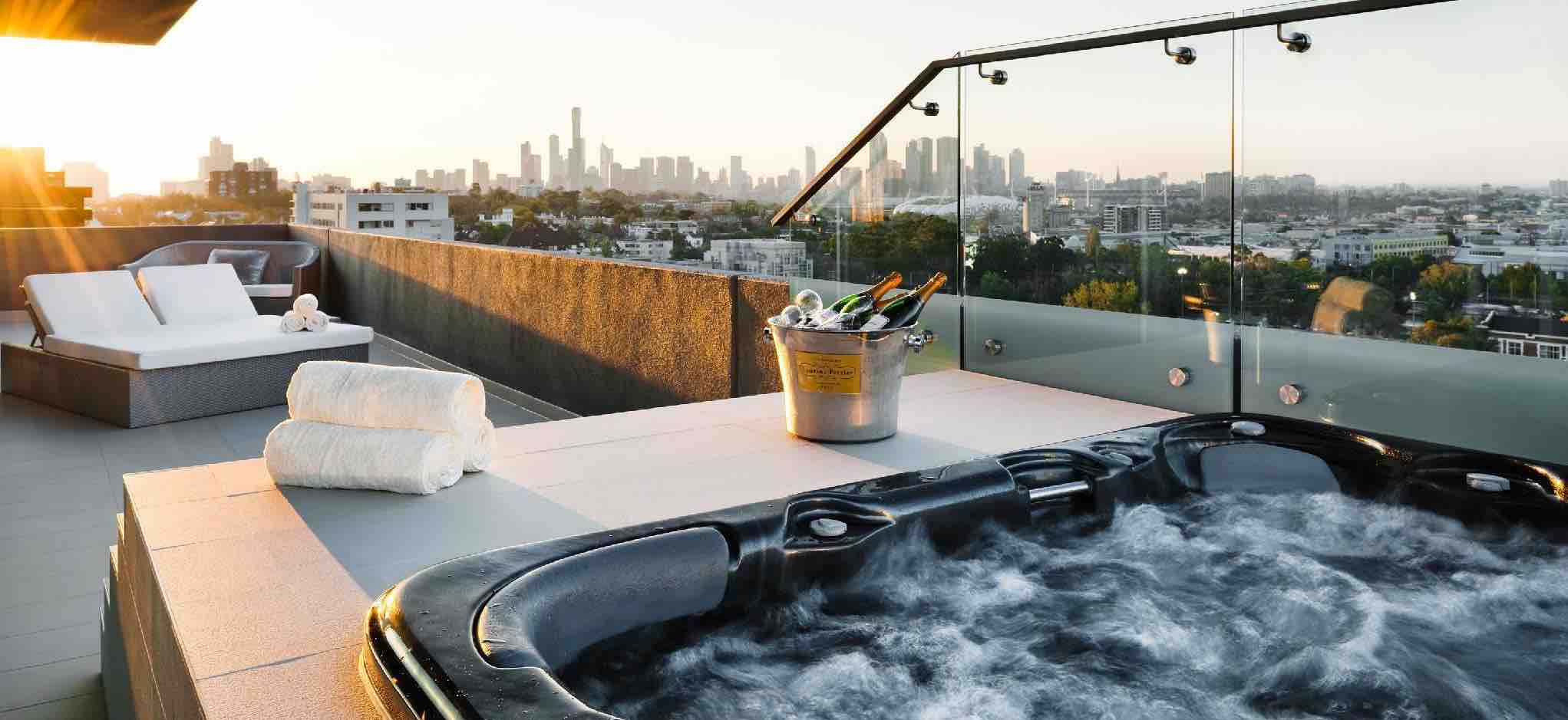 Photo of a jacuzzi with a few drinks and a bottle of Champagne outside on the terrace of a suite with a couple of loungers for sunbathing