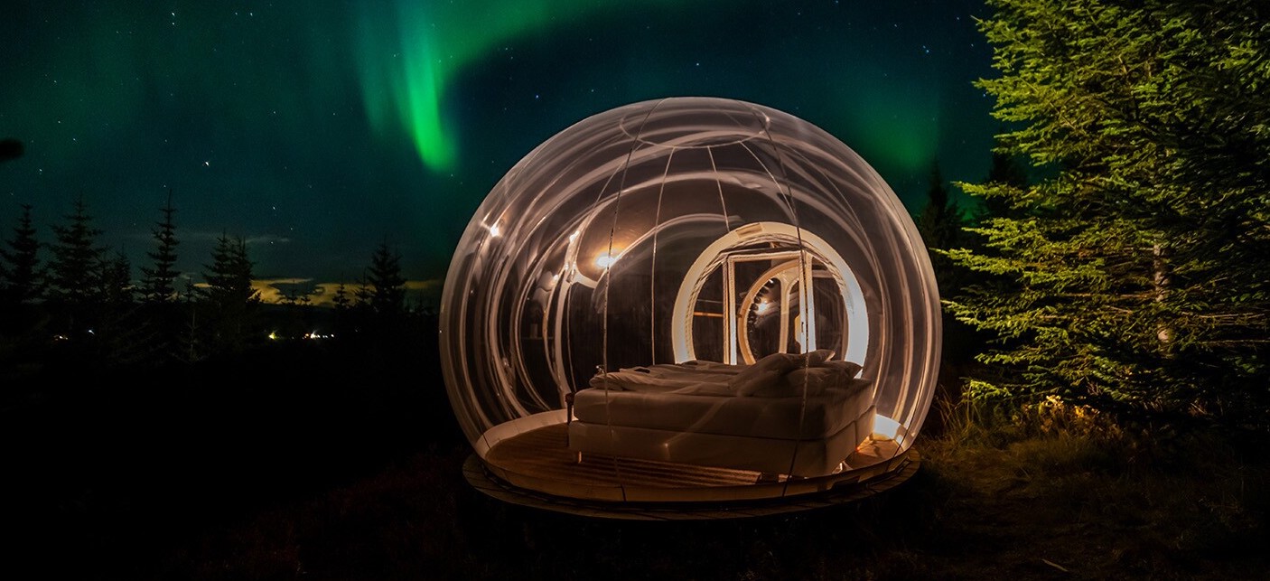 
A bubble hotel located in a forest with the green northern lights in the background