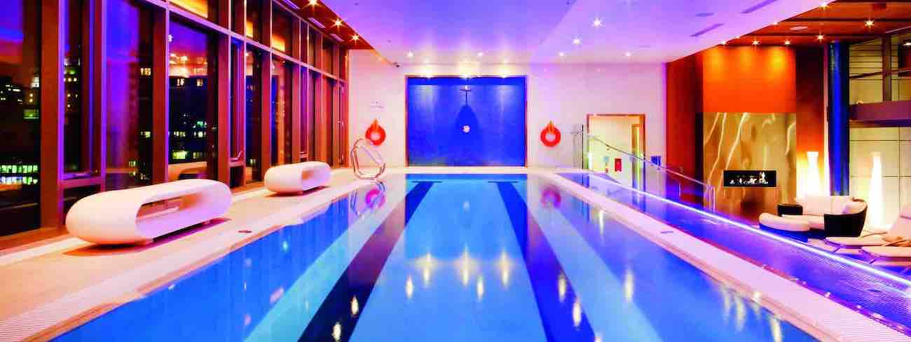 A room with a heated pool with chromotherapy lights