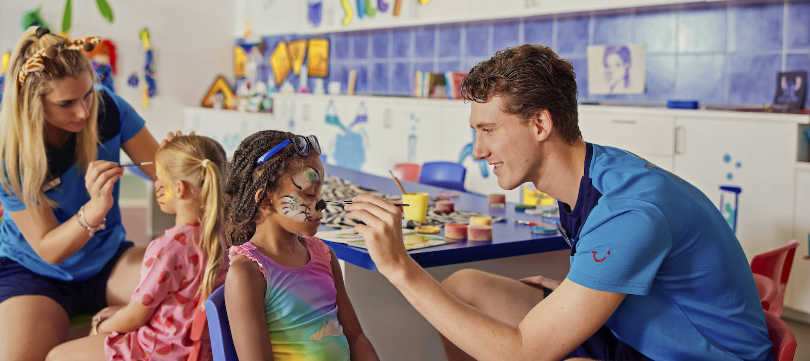 A boy and a girl doing makeup on a boy and a girl in a children's playroom in a hotel