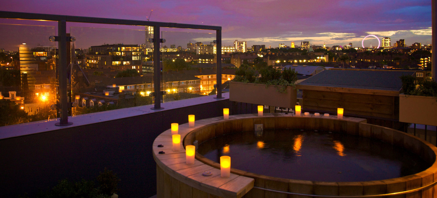 Photo of a circular jacuzzi in a room with views of the city and with some candles on the edge of the jacuzzi
