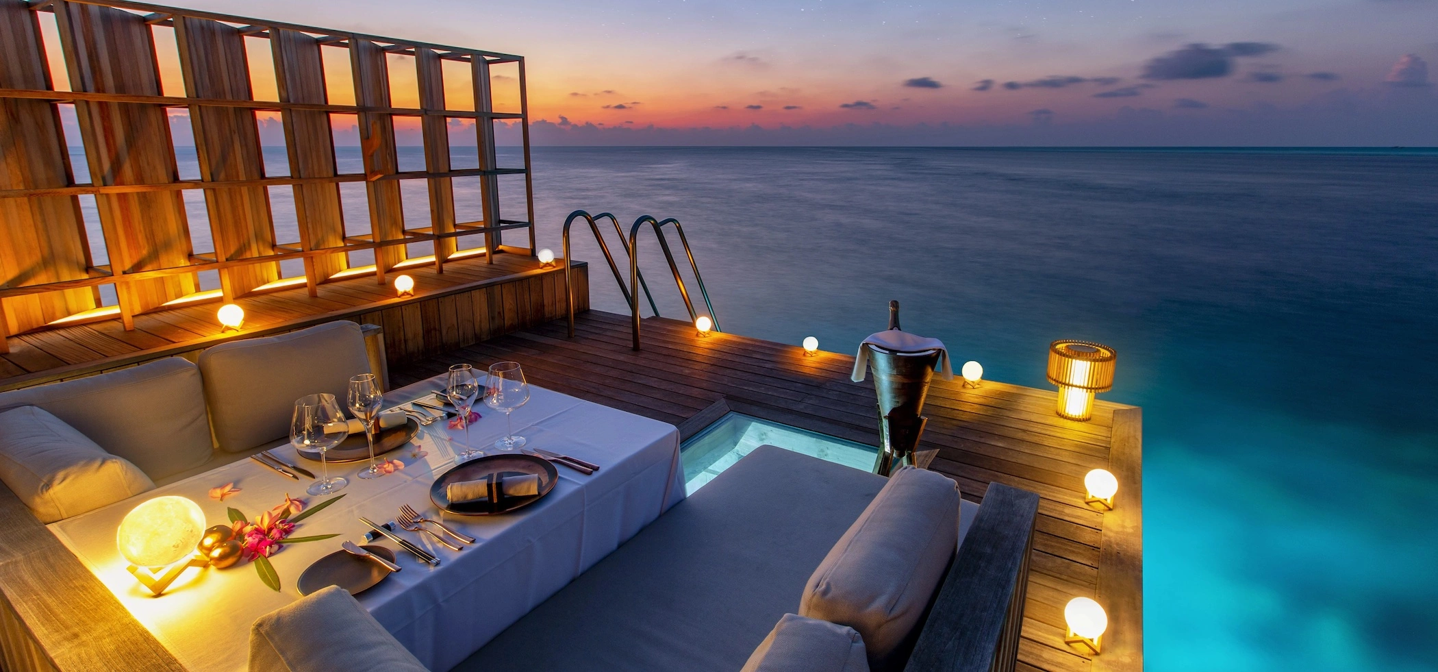 A romantic table prepared to eat on a wooden platform that is located over the sea and with fantastic views